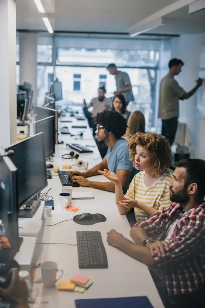 Group of computer programmers talking while working at IT office
